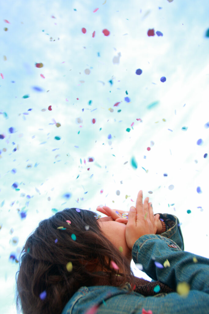 Frau wirft Konfetti in die Luft